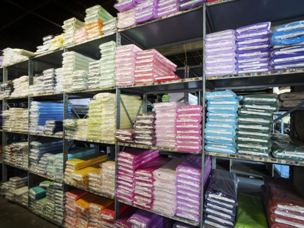 A rack of folded and packaged fabrics in various colors